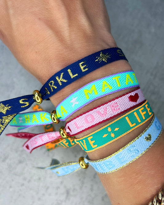 Dieses-Armband besteht aus sehr haltbarem Polyester und hat die Aufschrift "SPARKLE & SHINE". Die goldfarbene Stopper-Perle ist aus rostfreiem Stahl.