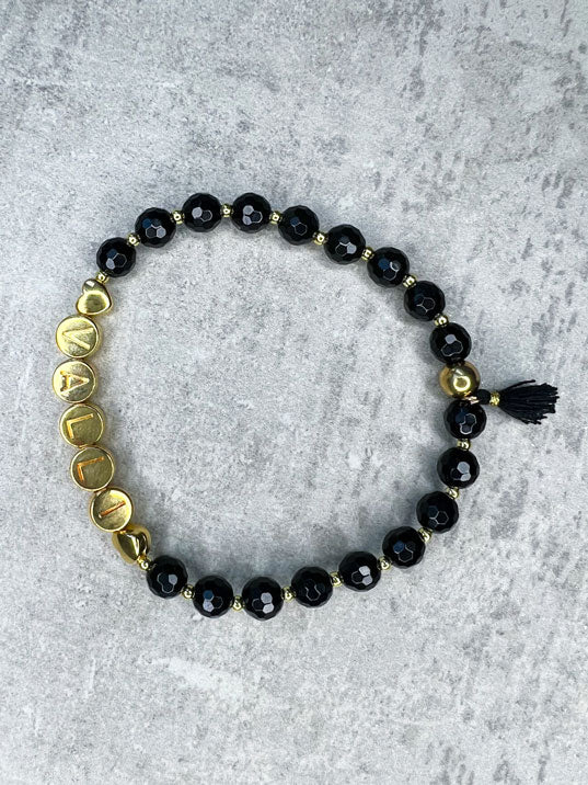 Heilstein-Armband aus wunderschönen, feinen und ausgesuchten Perlen! Dieses Armband ist handgearbeitet aus: schwarzen, facettierten Onyx-Perlen, goldfarbenen Edelstahlperlen, goldfarbenen Metall-Buchstabenperlen & einer goldfarbenen Edelstahlkugel. "Der Onyx stärkt das Selbstbewusstsein und Durchsetzungsvermögen, weshalb er keineswegs als schlechtes Omen angesehen werden sollte, sondern vielmehr als Schutzstein. Oft wird er auch als Trauerstein eingesetzt, da er Kraft und Trost spendet."
