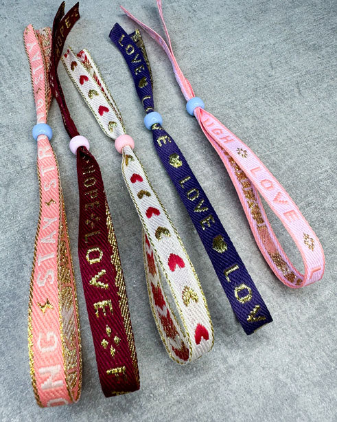 Dieses-Armband besteht aus sehr haltbarem Polyester und hat die Aufschrift "LIVE LAUGH LOVE". Die goldfarbene Stopper-Perle ist aus rostfreiem Stahl.