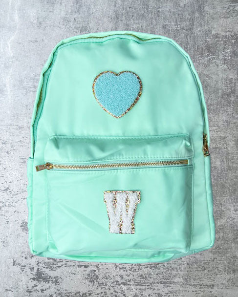 Der Nylonrucksack ist das It Piece unter unseren personalisierbaren Taschen. perfekt für Laptop, Ordner, Hefte und Co. geeignet, mit einer Innentasche sowie auf beiden Aussenseiten mit Taschen Die Schultergurte sind weich gepolstert und machen den Rucksack so auch für schwerere Inhalte. Das Aussenmaterial, Nylon, ist ausserdem wasserabweisend. Zum Personalisieren mit süßen Glitzer-Buchstaben-Patches, Smileys oder Herzen.