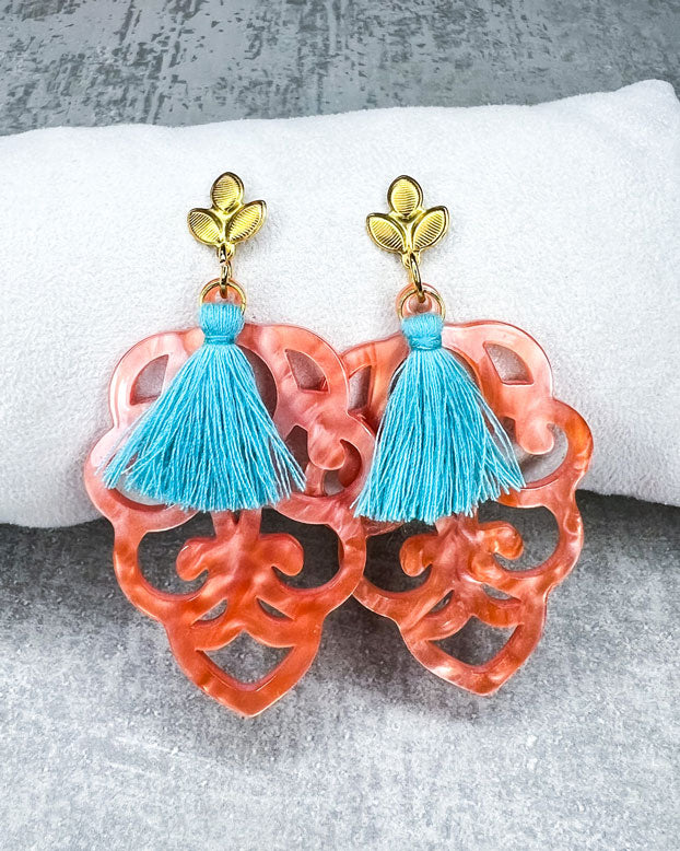 Dieser Ohrring ist gemacht mit: einem Ohrstecker aus rostfreiem Stahl in "Lilien-Optik", einem Ornament-Anhänger in der Farbe "Coral" und einer großen türkisen Quaste.