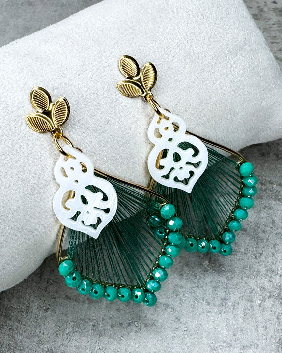 Dieser Ohrring ist gefertigt aus einem goldfarbenem Blüten-Stecker aus rostfreiem Stahl, einem mit grünen Glitzerperlen besetzen Anhänger und einem Perlmutt-Ornament-Anhänger.