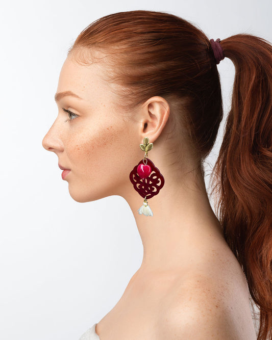 Dieser Ohrring ist gefertigt aus einem blütenförmigen Ohrstecker aus rostfreiem Stahl, einem Ornament-Anhänger in Rot, einem rot gefärbten Jade-Herz und einer Quaste in Creme.