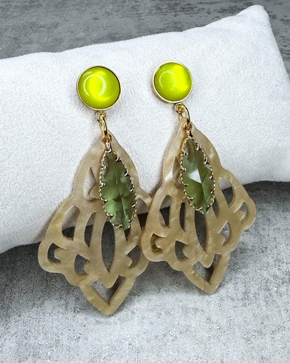 Dieser Ohrring ist gemacht mit:
einem goldfarbener "Polaris Steel" Ohrstecker mit einem gelb glänzenden Cabochon Stein, einem Ornament-Anhänger in der Farbe "Beige-Gold" und einem goldgefassten, grün facettierten Glas-Anhänger.
