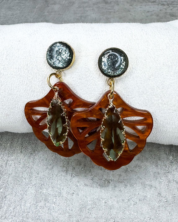 Dieser Ohrring ist gemacht mit:
einem goldfarbenen "Polaris Steel" Ohrstecker mit einem grün glitzernden Cabochon Stein, einem Ornament-Anhänger in der Farbe "Rosewood" und einem grün facettierten und gold gefassten Anhänger.