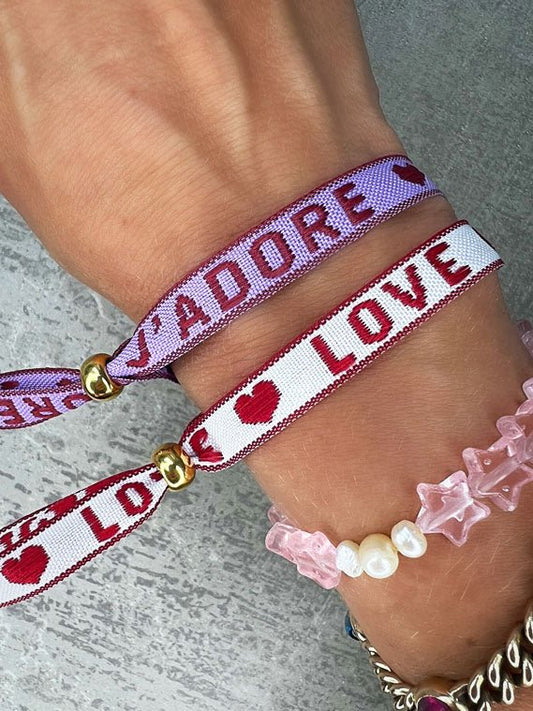 Dieses-Armband besteht aus sehr haltbarem Polyester und hat die Aufschrift "LOVE". Die goldfarbene Perle ist aus rostfreiem Stahl.