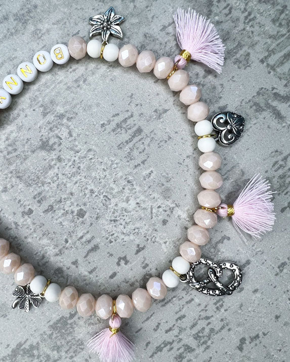 Wiesn-Halsband, Oktoberfest-Halsband, Von Hand gefertigter Schmuck für Dein Haustier.  Die Kette besteht aus beige glitzernden, facettierten Glasperlen, weißen Acrylperlen, weißen Acryl-Buchstabenperlen, osafarbenen Quasten, silberfarbenen Wiesn-Anhängern, sowie einer goldfarbenen Edelstahlkugel. 
