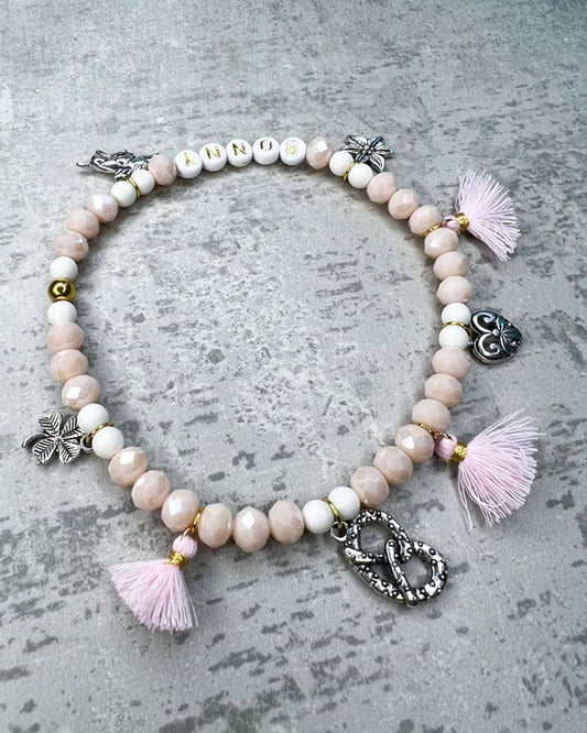 Wiesn-Halsband, Oktoberfest-Halsband, Von Hand gefertigter Schmuck für Dein Haustier.  Die Kette besteht aus beige glitzernden, facettierten Glasperlen, weißen Acrylperlen, weißen Acryl-Buchstabenperlen, osafarbenen Quasten, silberfarbenen Wiesn-Anhängern, sowie einer goldfarbenen Edelstahlkugel. 