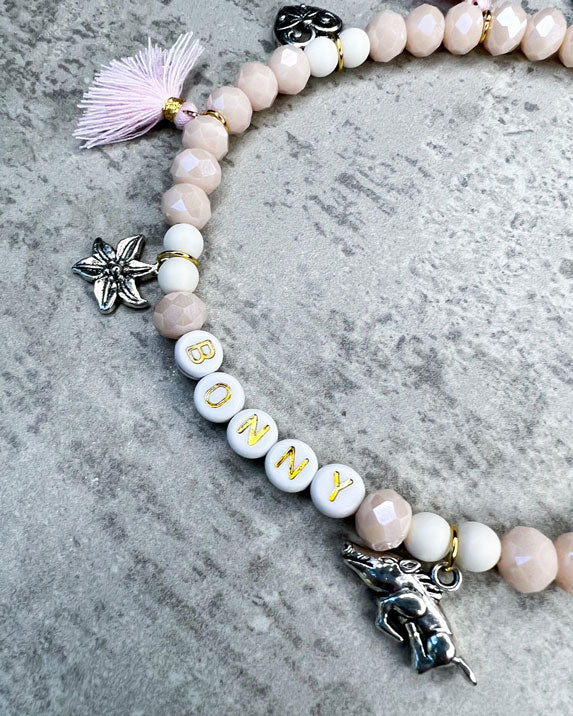 Wiesn-Halsband, Oktoberfest-Halsband, Von Hand gefertigter Schmuck für Dein Haustier.  Die Kette besteht aus beige glitzernden, facettierten Glasperlen, weißen Acrylperlen, weißen Acryl-Buchstabenperlen, osafarbenen Quasten, silberfarbenen Wiesn-Anhängern, sowie einer goldfarbenen Edelstahlkugel. 