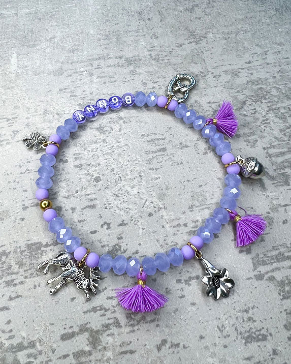 Von Hand gefertigter Schmuck für Dein Haustier.  Die Wiesn-Kette besteht aus lila glitzernden, facettierten Glasperlen, lilafarbenen Polymer, lila Acryl-Buchstabenperlen, lilafarbenen Quasten, silberfarbenen Wiesn-Anhängern, sowie einer goldfarbenen Edelstahlkugel. 