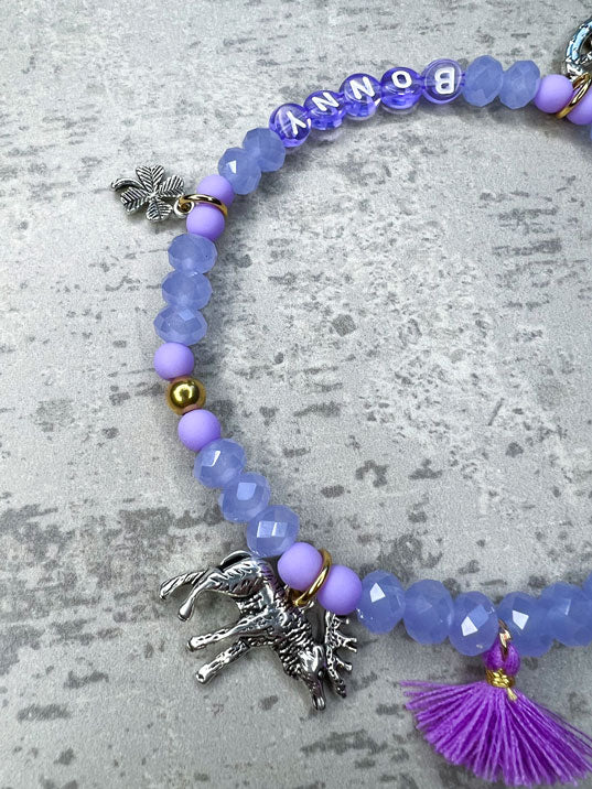 Von Hand gefertigter Schmuck für Dein Haustier.  Die Wiesn-Kette besteht aus lila glitzernden, facettierten Glasperlen, lilafarbenen Polymer, lila Acryl-Buchstabenperlen, lilafarbenen Quasten, silberfarbenen Wiesn-Anhängern, sowie einer goldfarbenen Edelstahlkugel. 