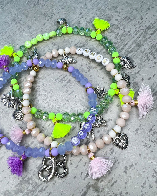 Von Hand gefertigter Schmuck für Dein Haustier.  Die Wiesn-Kette besteht aus lila glitzernden, facettierten Glasperlen, lilafarbenen Polymer, lila Acryl-Buchstabenperlen, lilafarbenen Quasten, silberfarbenen Wiesn-Anhängern, sowie einer goldfarbenen Edelstahlkugel. 