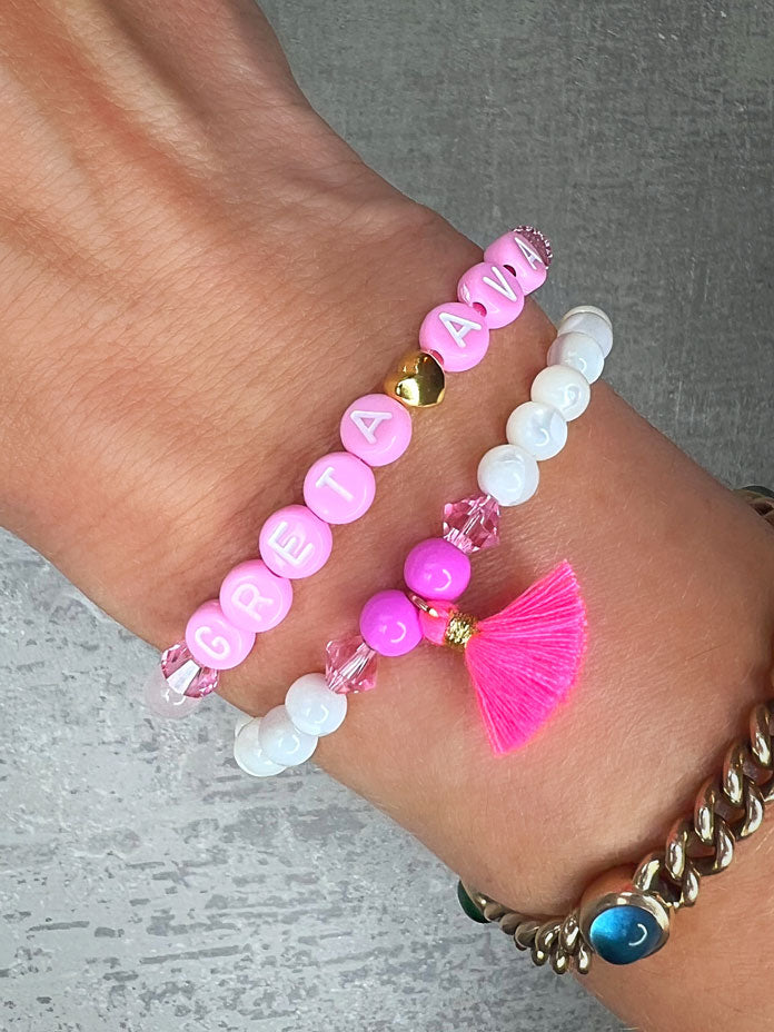 Heilstein-Armband mit wunderschönen, feinen und ausgesuchten Perlen.  Dieses Armband ist handgearbeitet und doppelt gebunden aus: rosafarbenen Rosenquarz-Perlen, pink glitzernden Swarovski-Perlen, einem goldfarbenem Herz, pinken, goldenen und rosafarbenen Glasperlen, weißen Perlmutt-Perlen, einer neon-pinken Quaste, einer goldfarbenen Edelstahl-Perle & Buchstaben aus Acryl in rosa.