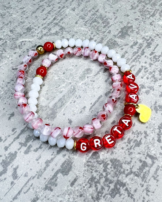 Doppeltes Armband mit wunderschönen, feinen und ausgesuchten Perlen.  Dieses Armband ist handgearbeitet aus: facettierten, weißen Glasperlen, Herzchen-Glasperlen, rote Glasperlen, einem Edelstahl-Herzanhänger, einer goldfarbenen Edelstahl-Perle & Buchstaben aus Acryl rot transparent.