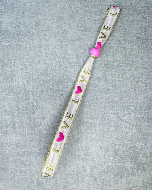 Dieses-Armband besteht aus sehr haltbarem Polyester und hat die Aufschrift "PINK LOVE". Die goldfarbene Stopper-Perle ist aus rostfreiem Stahl.