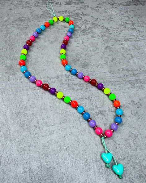 Eine von uns handgefertigte Handykette aus ausgesuchten und Perlen – damit Du&nbsp;nie wieder&nbsp;Dein Handy liegen lässt!

Gefertigt aus:
kunterbunten, neonfarbenen Acryl-Perlen (sehr leicht),
kleinen bronzefarbenen Acrylperlen in den Zwischenräumen
und einer langen Quaste in Peach.

Diese kurze Handykette ist ca. 20 cm lang – wenn Du aber eine andere Länge benötigst, schreib uns gerne in den Anmerkungen.

Die Kette ist auf langlebiges Shamballa-Band gezogen.