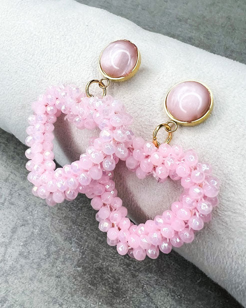 Dieser Ohrring ist gefertigt aus einem Cabochon-Ohrsstecker aus rostfreiem Stahl mit einem glänzenden, rosanen Cabochon-Stein und einem glitzernden Facetten-Herz-Anhänger in der Farbe "Baby Rose".
