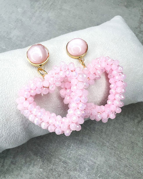Dieser Ohrring ist gefertigt aus einem Cabochon-Ohrsstecker aus rostfreiem Stahl mit einem glänzenden, rosanen Cabochon-Stein und einem glitzernden Facetten-Herz-Anhänger in der Farbe "Baby Rose".