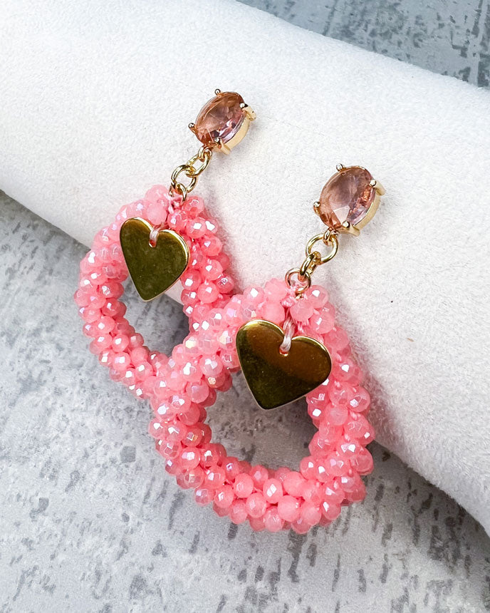Ohrstecker mit einem pfirsichfarbenen, facettierten Glasstein, einem glitzernden Facetten-Perlen-Anhänger in der Farbe "Coral Pink" und einem goldfarbenem Herz-Anhänger.