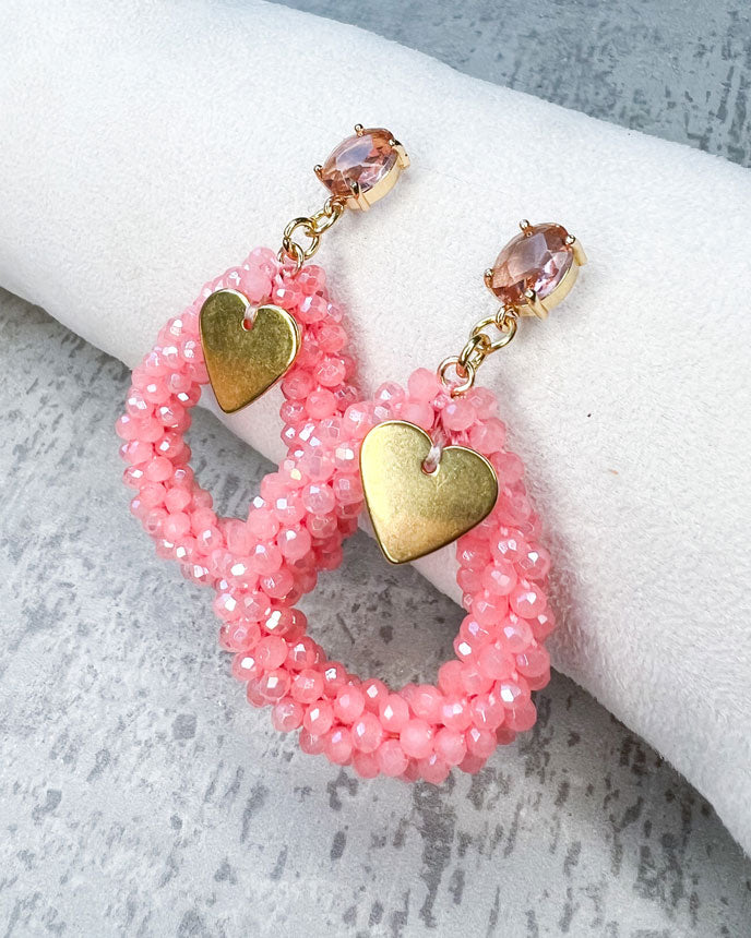 Ohrstecker mit einem pfirsichfarbenen, facettierten Glasstein, einem glitzernden Facetten-Perlen-Anhänger in der Farbe "Coral Pink" und einem goldfarbenem Herz-Anhänger.