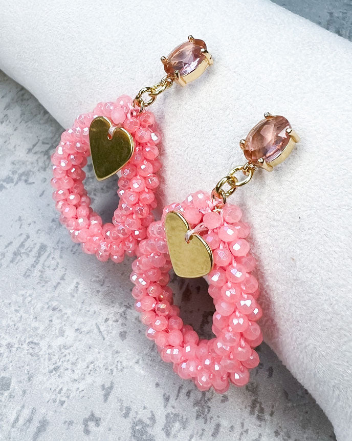 Ohrstecker mit einem pfirsichfarbenen, facettierten Glasstein, einem glitzernden Facetten-Perlen-Anhänger in der Farbe "Coral Pink" und einem goldfarbenem Herz-Anhänger.