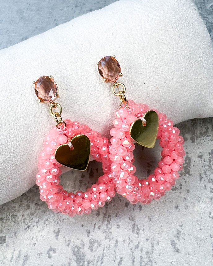 Ohrstecker mit einem pfirsichfarbenen, facettierten Glasstein, einem glitzernden Facetten-Perlen-Anhänger in der Farbe "Coral Pink" und einem goldfarbenem Herz-Anhänger.