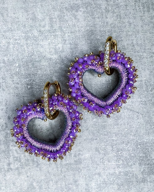 Dieser Ohrring ist gefertigt aus einem Edelstahl Ohrring mit Strassbesatz und einem glitzernden Facetten-Herz-Anhänger in der Farbe "Purple". Der Anhänger kann abgemacht und der Strass-Ohrring somit auch einzeln getragen werden.
