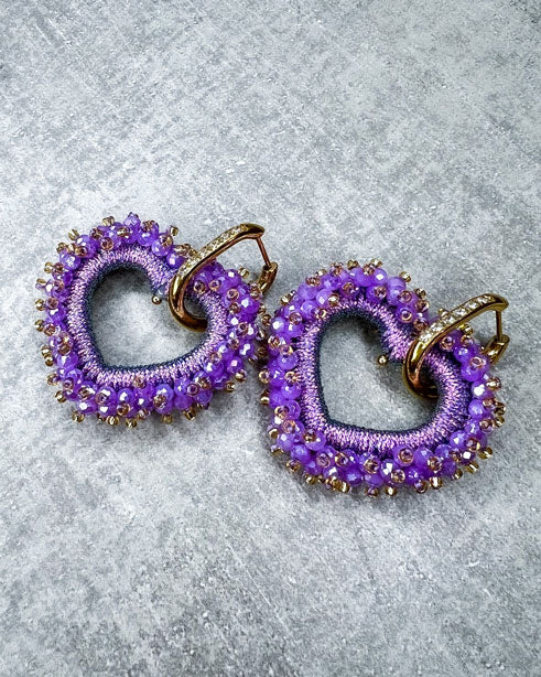 Dieser Ohrring ist gefertigt aus einem Edelstahl Ohrring mit Strassbesatz und einem glitzernden Facetten-Herz-Anhänger in der Farbe "Purple". Der Anhänger kann abgemacht und der Strass-Ohrring somit auch einzeln getragen werden.