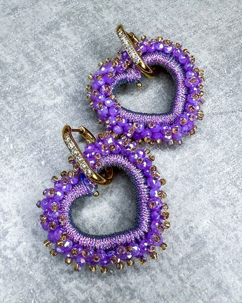 Dieser Ohrring ist gefertigt aus einem Edelstahl Ohrring mit Strassbesatz und einem glitzernden Facetten-Herz-Anhänger in der Farbe "Purple". Der Anhänger kann abgemacht und der Strass-Ohrring somit auch einzeln getragen werden.