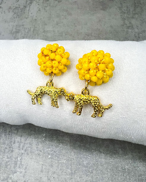 Die Ohrringe bestehen aus: einem Ohrstecker mit fascettierten, gelben Glasperlen und einem grolfarbenem Leoparden als Anhänger.