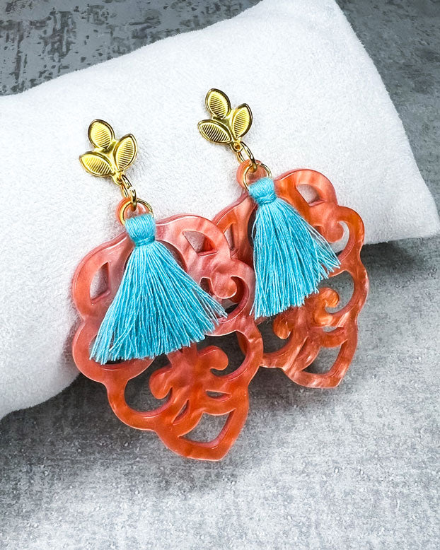 Dieser Ohrring ist gemacht mit: einem Ohrstecker aus rostfreiem Stahl in "Lilien-Optik", einem Ornament-Anhänger in der Farbe "Coral" und einer großen türkisen Quaste.