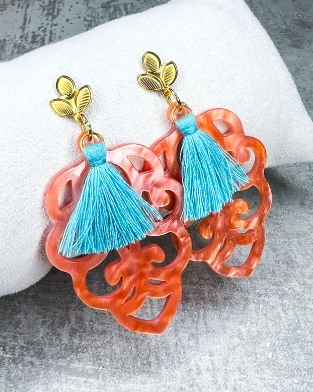 Dieser Ohrring ist gemacht mit: einem Ohrstecker aus rostfreiem Stahl in "Lilien-Optik", einem Ornament-Anhänger in der Farbe "Coral" und einer großen türkisen Quaste.