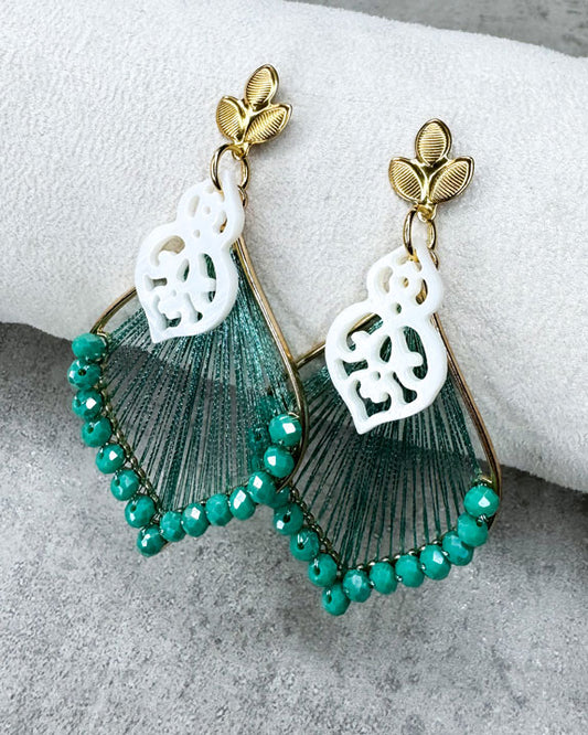Dieser Ohrring ist gefertigt aus einem goldfarbenem Blüten-Stecker aus rostfreiem Stahl, einem mit grünen Glitzerperlen besetzen Anhänger und einem Perlmutt-Ornament-Anhänger.
