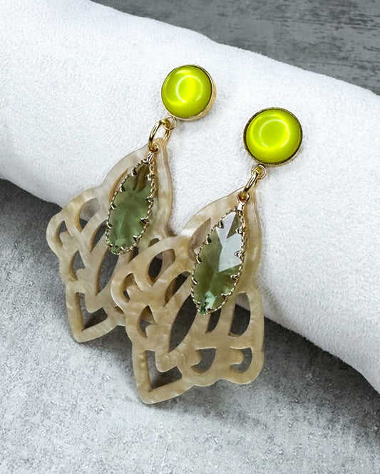 Dieser Ohrring ist gemacht mit:
einem goldfarbener "Polaris Steel" Ohrstecker mit einem gelb glänzenden Cabochon Stein, einem Ornament-Anhänger in der Farbe "Beige-Gold" und einem goldgefassten, grün facettierten Glas-Anhänger.