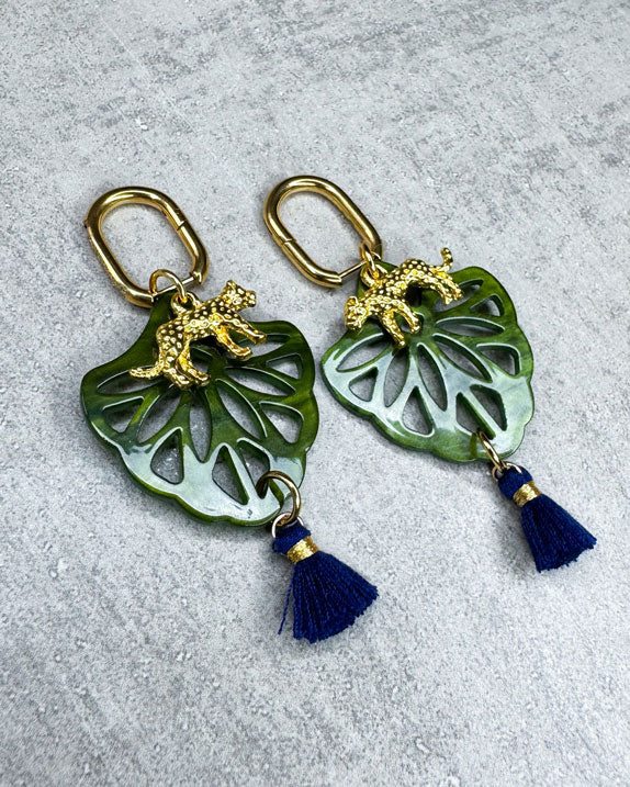 Dieser Ohrring ist gefertigt aus einer Creole aus rostfreiem Stahl mit weißen Zirkonia-Glitzersteinen vorne, einem Ornament-Anhänger in Green, einem goldfarbenen Panther als Anhänger und einer Quaste in Dunkelblau.