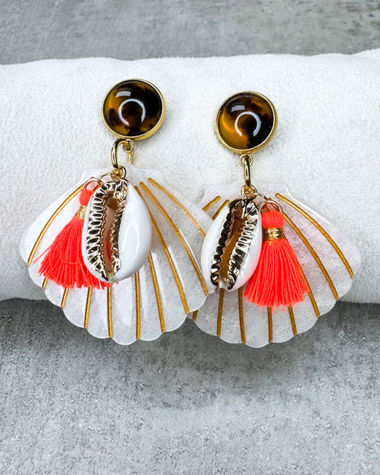 Dieser Ohrring ist gefertigt aus einem Polaris Steel Ohrstecker, einem Cabochon-Stein in Schildpatt-Optik, einem weiß glitzernden Muschel-Anhänger aus Acryl, einer gold verzierten Muschel als Anhänger und einer neon orangenen Quaste.
