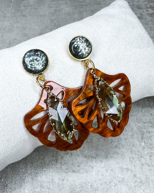 Dieser Ohrring ist gemacht mit:
einem goldfarbenen "Polaris Steel" Ohrstecker mit einem grün glitzernden Cabochon Stein, einem Ornament-Anhänger in der Farbe "Rosewood" und einem grün facettierten und gold gefassten Anhänger.