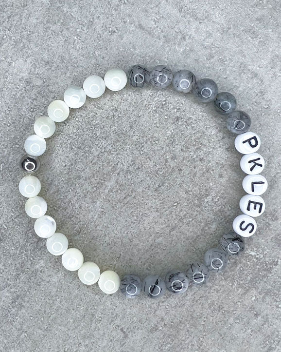 Diese Armband ist handgemacht aus wunderschönen, feinen und ausgesuchten Perlen!  Dieses Armband ist handgearbeitet aus: runden, grauen Turmalinquarz-Edelsteinen, weißen Perlmutt-Perlen, weißen Acryl-Buchstaben-Perlen und einer silbernen Edelstahlkugel.