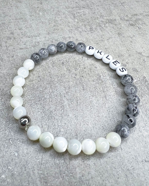 Diese Armband ist handgemacht aus wunderschönen, feinen und ausgesuchten Perlen!  Dieses Armband ist handgearbeitet aus: runden, grauen Turmalinquarz-Edelsteinen, weißen Perlmutt-Perlen, weißen Acryl-Buchstaben-Perlen und einer silbernen Edelstahlkugel.