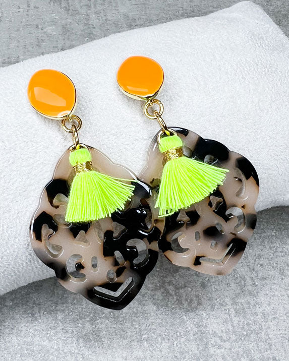 Dieser Ohrring ist handgefertigt für Euch!  Er besteht aus: einem länglichen Ohrstecker in Neon-Orange mit einem schildpatt-farbenen Ornament-Anhänger und einer neongelben Quaste.